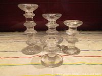 Front view of four Festivo candlesticks showing varying heights and ring counts