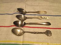 Four collector spoons laid out to show full length and relative sizes