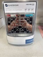 Front view of sealed retail package showing Glacier Bay branding, square chrome LED showerhead