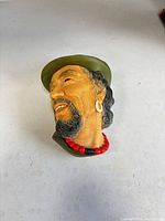 Front angled view of resin head bust showing facial features, hat and necklace