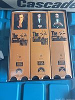 Front view of three VHS spines inside slipcase, showing titles, logos and catalog numbers