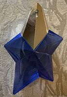 Front view of blue star-shaped perfume bottle with silver cap