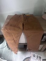 Front view of brown Carhartt work pants laid flat