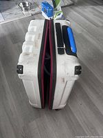 Side view of white Columbia suitcase showing pink zipper expansion, four-wheel base, visible scuffs