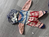 Flat rag doll with patchwork dress showing overall wear