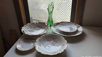 Group shot showing all porcelain dishes and green swung glass vase on table
