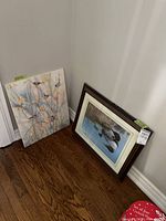 Canvas bird painting and framed bird print leaning against wall