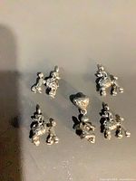 Group view of silver-tone charms showing five poodles and central heart with angel