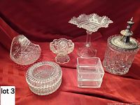 Group view of all six clear cut glass items including jar with metal lid, compote, footed bowl, ashtray, square box