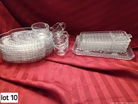 Stack of oval swirl plates with four clear cups and stack of rectangular plates/platter