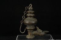 Left side view of entire lamp showing tiered body, chain and spout