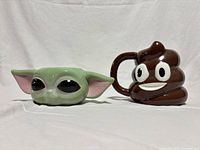 Front view of both mugs showing Grogu and Poop Emoji designs