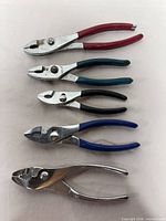 Five slip-joint pliers laid out showing size progression and handle colors