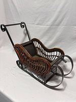Front angled view of wicker and metal sleigh showing overall design