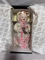 Doll secured inside original box with tissue wrap and certificate visible
