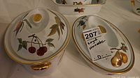 Covered dish with lid on and second view of lid showing fruit motifs and gold trim
