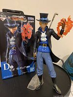 Front view of Sabo figure with flame effect, cane, stand and original box visible