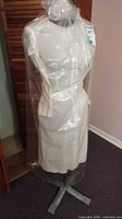 Full view of fabric-covered dress form mannequin torso on metal cross base wrapped in protective plastic