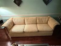 Front view of beige chenille three-seat sofa showing cushions and wood arm trim