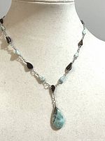 Necklace displayed on bust showing stone arrangement and pendant