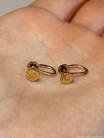 Both earrings resting on palm showing overall design and scale