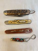 Four closed pocket knives lined horizontally