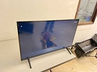 Front view of Vizio TV powered on showing loading screen on stand