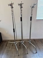 three silver metal C-stands fully assembled