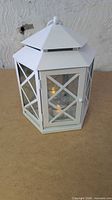 Front view of white hexagonal lattice lantern with LED tealights visible through glass