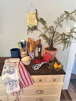 Full view of lot on countertop showing utensils, holders, bowls, towels, spoon rests, faux plant, glass bottle