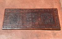 Full view of leather-topped table surface showing three embossed Mesoamerican figures and geometric border