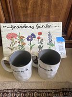 Two ceramic mugs and one floral wall plaque displayed