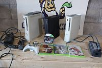 Overview showing three consoles, controller, power supplies, games