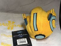 Rear view of Probe plush, hang tag front, and StarCraft II drawstring bag