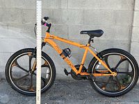 Side profile of orange Mongoose mountain bike with mag wheels