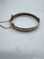 Full view of hinged sterling bangle with safety chain attached