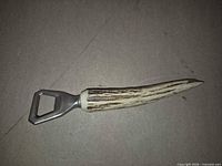 Full view of antler handle bottle opener on flat surface