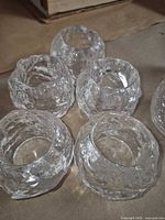 Five clear textured glass tealight holders grouped on surface