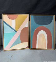 Front view of both framed abstract artworks standing side by side