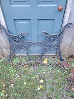 Pair of cast iron ornate bench ends leaning against door