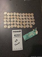 All 49 dimes laid out in rows beside empty green bank roll wrapper
