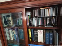 Books and CDs on wooden shelf showing variety of titles, slip-case sets and disc cases