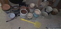 Front view of assorted pots, saucers, yellow fly swatter on floor