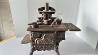 Front view of Crescent cast iron toy stove with accessories on top