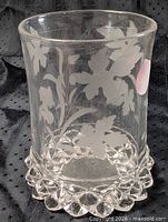 Front view of clear glass cup showing etched oak leaf design and scalloped base