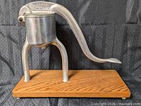 Full view of aluminum juicer on oak base