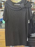 Full view of black cable-knit sweater dress on hanger