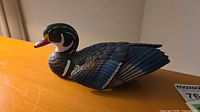 Left side of carved multicolor duck decoy on tabletop