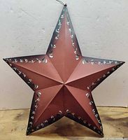 Front view of red metal star showing floral decoration and 3-D form