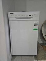 Front view of white Frigidaire dishwasher with control panel and factory stickers